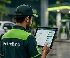 A station manager in a PetroBind uniform using a tablet on the forecourt